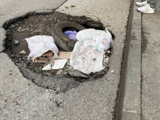 В Ростове на 2-й Пятилетке глубокие ямы на дороге отметили покрышками и мешками с плиткой